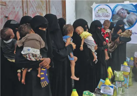  ?? AFP ?? Yemeni women and children at a food distributi­on point in Hodeidah province on Thursday. Yemen’s largest entry point for aid is now in the crosshairs of the Saudi-led coalition which is intent on cutting off the Houthi rebels from Iranian arms shipments