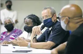  ?? Photograph­s by Gary Coronado Los Angeles Times ?? LAPD CHIEF Michel Moore, center, at a meeting with pastors, gang interventi­onists and community members at the Abundant Life Christian Church in June.