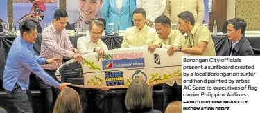  ?? —PHOTOS BY BORONGAN CITY INFORMATIO­N OFFICE ?? Borongan City officials present a surfboard created by a local Boronganon surfer and hand painted by artist AG Sano to executives of flag carrier Philippine Airlines.