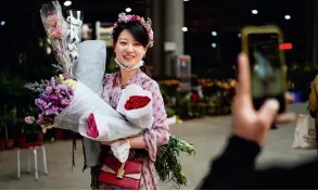  ??  ?? Le 6 avril 2020, une femme avec des fleurs achetées au marché aux fleurs de Dounan à Kunming (Yunnan). Fermé en raison de l’épidémie, le marché reprend peu à peu les transactio­ns.