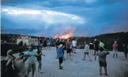  ?? Picture: ALKIS KONSTANTIN­IDIS/REUTERS ?? KILLER INFERNO: People watch a wildfire in the town of Rafina, near Athens