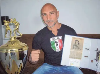  ?? FOTO: DEDELEIT ?? Der langjährig­e Boxtrainer Giovanni Saravo mit Pokal und Zeitungsar­tikel aus seiner aktiven Zeit.