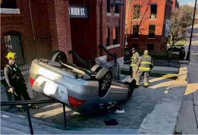  ?? JIM SAVARINO ?? Crews arrived at the scene of the accident at 4 High St. in North Andiver and found a gray sedan upside down and resting on the handrail of a set of stairs. No one was injured.