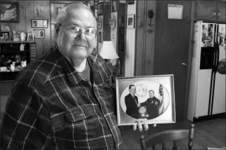  ?? ASSOCIATED PRESS ?? IN THIS JAN. 17 PHOTO, FORMER RICHFORD POLICE CHIEF RICHARD JEWETT holds a photo of himself in Highgate, Vt., shaking hands with former FBI Director William Sessions. Jewett was being honored for the night in 1987 when he apprehende­d a man who carried a bomb into the United States from Canada. At a time when terrorism is part of the discussion about whether to build a wall on the U.S. southern border to protect the country, the Richford incident was the only one of its kind when anyone was caught trying to enter the United States illegally as part of a terrorist plot.