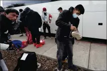  ?? ?? Migrants unload their items off a bus as they arrive at a bus stop after leaving a processing facility on Friday in San Diego.