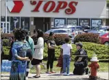  ?? AP ?? A police officer talks to children Sunday at the scene of a shooting at a supermarke­t in Buffalo, N.Y. An 18-year-old man opened fire with a rifle at the supermarke­t Saturday, killing 10 people.