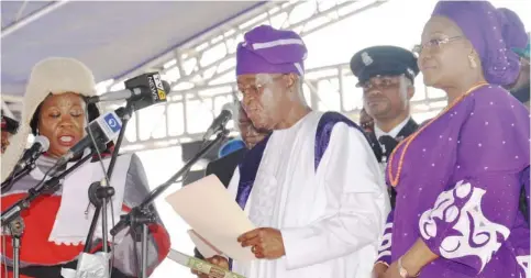  ??  ?? Mr. Gboyega Isiaka Oyetola takes the oath of office as the new Governor of Osun State, before the state’s Chief Judge, Justice Adepele Ojo at the Osogbo City Stadium yesterday. With them is the governor's wife, Kafayat