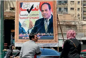  ?? AP ?? People walk past a banner supporting proposed amendments to the Egyptian constituti­on with a poster of Egyptian President Abdel-Fattah el-Sissi in Cairo.