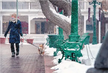  ?? EDDIE MOORE/JOURNAL ?? Kirstin Lurtz of Portland, Oregon, and her dog Cooper walk through the Santa Fe Plaza on Wednesday. Lurtz said she is visiting Santa Fe for a month.