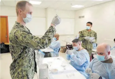  ?? SETH WENIG / REUTERS ?? Personal de la Armada de EEUU prepara dosis de la vacuna en un centro del barrio neoyorquin­o de Queens.