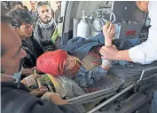  ??  ?? An Afghan policeman, right, keeps watch at the site of a suicide attack on a Shia cultural centre, in Kabul, which killed 41 people, and injured 84 more, including this woman, left, in an ambulance on her way to hospital