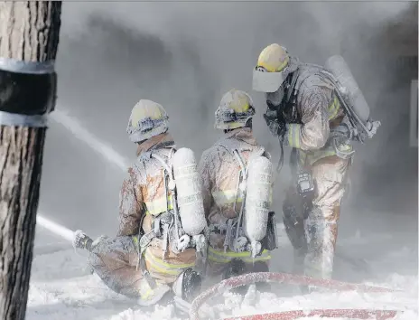  ?? TROY FLEECE ?? Regina fire crews are covered in ice Monday as they battle a house fire. The blaze also damaged a couple of adjacent homes.