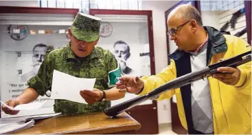  ?? Fotos de Nick Wagner / AP ?? Un cliente valida su compra con un soldado antes de salir de la única tienda de armas que hay en México.