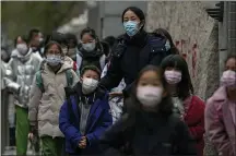  ?? ANDY WONG — THE ASSOCIATED PRESS ?? Students wearing face masks to protect from COVID-19ARE escorted by a teacher as they leave school after classes in Beijing. Despite the global worry, scientists caution that it’s still unclear whether the omicron COVID-19 variant is more dangerous than other versions of the virus that has killed more than 5 million people.
