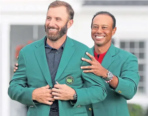  ??  ?? RECORD-BREAKER: Dustin Johnson is presented with his Green Jacket by 2019 champion Tiger Woods.