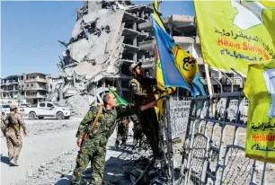  ?? AFP ?? Members of the Syrian Democratic Forces, backed by US special forces, place their flags at the iconic Al Naim Square in Raqqa on Tuesday. —