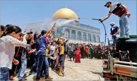  ?? REUTERS ?? FAITHFULS: Palestinia­n men spray water on children to cool them down before prayers on the third Friday of the holy month of Ramadan near the Dome of the Rock, on the compound known to Muslims as Noble Sanctuary and to Jews as Temple Mount, in...