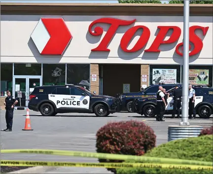  ?? USMAN KHAN — AFP/GETTY IMAGES/ TNS ?? Police sit in front of a Tops Grocery store in Buffalo, N.Y., on May 15, 2022. Grieving residents from the city of Buffalo held vigils Sunday
after a white gunman who officials have deemed “pure evil” shot dead 10 people at a grocery store in a racially-motivated rampage.