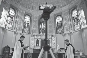  ?? EMILY LESHNER/ASSOCIATED PRESS FILE PHOTO ?? The Rev. Steven Paulikas, right, and curate Spencer Cantrell deliver an evening prayer service over Facebook Live in March at All Saints’ Episcopal Church in Brooklyn, N.Y., amid the pandemic.