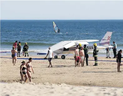  ?? ARMANDO FRANCA / THE ASSOCIATED PRESS ?? People walk by a plane resting by the sea after an emergency landing at Sao Joao beach in Costa da Caparica, outside Lisbon, Wednesday. The plane made the landing on a packed beach, killing a man and a child who were sunbathing.