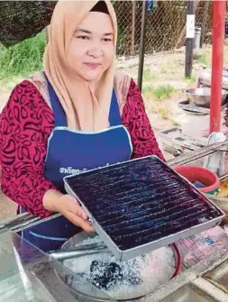  ?? PIC BY SYAHERAH MUSTAFA ?? Wan Suriana Wan Ali showing a tray of ‘kerbau guling’ at her stall in Rantau Panjang yesterday.