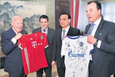 ?? PANG XINGLEI / XINHUA ?? Premier Li Keqiang meets German Vice-Chancellor and Foreign Minister Sigmar Gabriel (second from left) and receives soccer club jerseys from the visiting German delegation in Beijing on Wednesday.