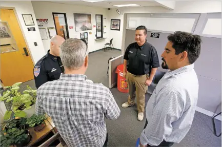  ?? PHOTOS BY LUIS SÁNCHEZ SATURNO/THE NEW MEXICAN ?? ABOVE: Santa Fe Police Department Deputy Chief Ben Valdez, center, speaks Friday with pastor Victor Gutierrez of Santa Fe Baptist Church, right, and Mike Hodgkinson of Santa Fe at the police station. Gutierrez was donating gift cards to the officers.