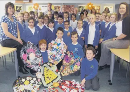  ??  ?? BUZZING: Children and staff from Oakdale Primary School proudly show off their giant flower on their visit to the Anglia Co-operative bee hives, watched by representa­tives of the Peterborou­gh and District Beekeepers’ Associatio­n.