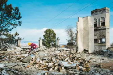  ?? ERIN SCHAFF/THE NEW YORK TIMES ?? A person looks for items Jan. 4 at the site of a home destroyed by a wildfire in Boulder, Colo.