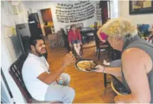  ??  ?? Volunteer Isabelle Houlbreque offers homemade cookies to Juan Cruz. Casa de Paz visits detainees and picks them up when they are released and gives them a place to stay, a meal, access to computers and transporta­tion to get back to their families.