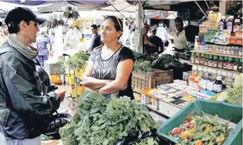  ??  ?? ► Una vendedora habla con cliente en un mercado en Rubio.