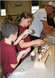  ??  ?? St. Francis Academy students Liam Conrad and Colleen Burr work on making the students’ show cones during the Bally school’s annual Dairy Day celebratio­n.