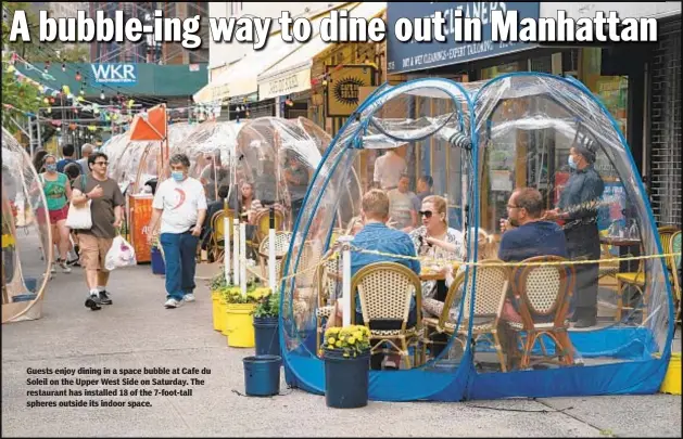  ??  ?? Guests enjoy dining in a space bubble at Cafe du Soleil on the Upper West Side on Saturday. The restaurant has installed 18 of the 7-foot-tall spheres outside its indoor space.