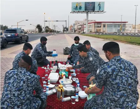  ?? SPA ?? Members of Saudi security forces in Tabuk break their fast on a sidewalk while on duty to enforce the COVID-19 lockdown on Friday.