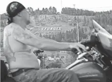  ?? TREVOR HUGHES, USA TODAY ?? A shirtless rider on Main Street cruises past the Sturgis sign during an evening ride on the wide pavement of the Black Hills.