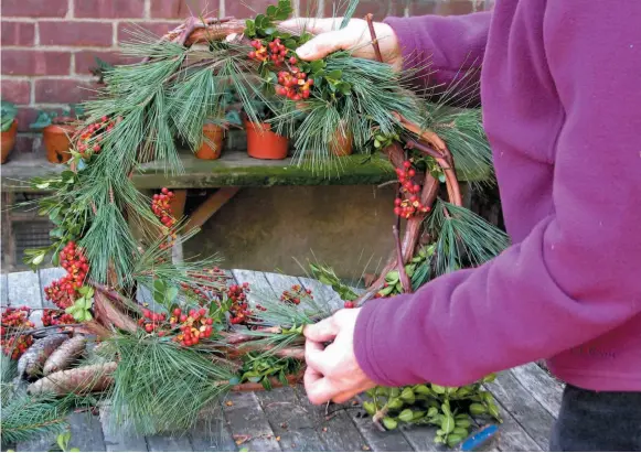  ?? AP FILE PHOTO ?? This undated photo shows the wreath being constructe­d in New Paltz, N.Y. Wreaths are a staple of holiday decor, which you can personaliz­e by selecting non-traditiona­l materials for ribbons and the boughs of the wreath, Terrain creative director Greg Lehmkuhl says.