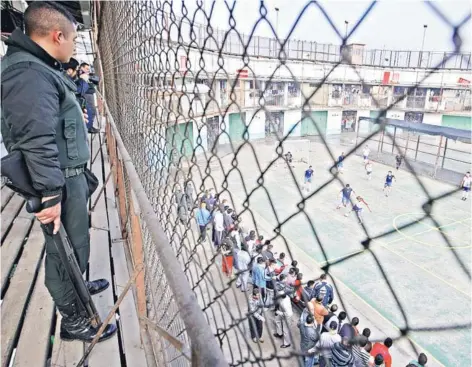  ??  ?? ► Gendarme observa a un grupo de reos jugando fútbol en la ex Penitencia­ría.