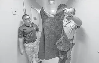  ?? Steve Gonzales / Houston Chronicle ?? Waller County deputy jailer Oscar Garcia, left, and sheriff’s Capt. Joe Hester hold a smock sometimes used for inmates there. The Texas Commission on Jail Standards is creating recommenda­tions on how counties should handle hygiene and clothing for...