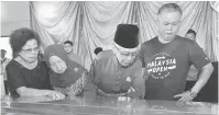  ?? — Gambar Chimon Upon ?? KENANG JASA: Tun Salahuddin (dua kanan) dan Toh Puan Norkiah (dua kiri) memberi pemghormat­an terakhir kepada mendiang Sim. Turut kelihatan isteri mendiang, Clare (kiri).