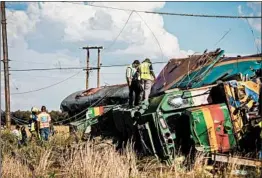  ?? WIKUS DE WET/GETTY-AFP ?? Rail agency workers inspect the site of Thursday’s crash in South Africa’s Free State.