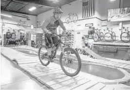  ?? PATRICK CONNOLLY/ORLANDO SENTINEL PHOTOS ?? Shawn Lukens, owner of Adrenaline BikeWorks, rides on the pump track within his Mount Dora shop.