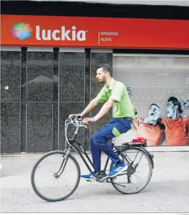  ?? J. Á. GARCIA ?? Un ciclista cruza la puerta de una casa de apuestas en Sevilla.