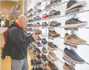  ?? RYAN REMIORZ / THE CANADIAN PRESS ?? Stephane Tsar shops for shoes at the Atmosphere sporting goods store Monday in St. Sauveur, Quebec. Retail stores
outside the greater Montreal area have been allowed to reopen after weeks of forced closure due to COVID-19.