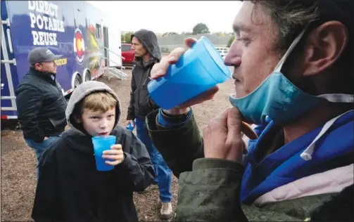  ?? (AP/Brittany Peterson) ?? Connor Sonnenberg (foreground left) and Billy Kinn (foreground right) drink wastewater that was sterilized Oct. 14 at the PureWater Colorado Mobile Demonstrat­ion using a method that involves carbon-based purificati­on in Colorado Springs, Colo.