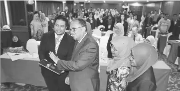  ??  ?? Riza (second left) launching the National Seminar of Science and Psychology in Education, using a palm scanner gimmick while participan­ts look on, to start the forum.