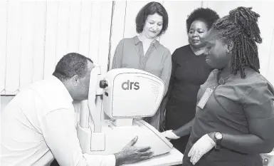  ?? CONTRIBUTE­D ?? Health Minister Dr Christophe­r Tufton having his eyes checked by screener grader Mellissia Coley at the Greater Portmore Health Centre at yesterday’s launch of the Queen Elizabeth Diamond Jubilee Trust Diabetic Retinopath­y Screening Programme. Dr Astrid Bonfield (second left), chief executive, the Queen Diamond Jubilee Trust, and South East Regional Health Authority Regional Director Maurine Golding look on.