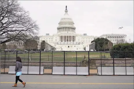  ?? Patrick Semansky / Associated Press ?? A woman walks past security fencing protecting the West Front of the U.S. Capitol in Washington, Friday as preparatio­ns take place for President-elect Joe Biden's inaugurati­on after supporters of President Donald Trump stormed the building.