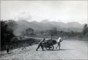  ?? SUBMITTED PHOTO ?? A Marine from the Troui CAP compound pushing/ helping a civilian move an ox cart. This view is from the bridge looking south toward Phu Loc. The building in the background on right side of Highway 1 is the old railroad station, which was used as an assembly point for marines returning and leaving for patrols in the Troui Valley.