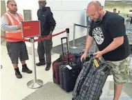  ?? ASSOCIATED PRESS ?? Dan Kovacs retrieves some of the luggage he left behind when shooting erupted at Fort Lauderdale’s airport.