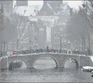  ?? AP ?? A man crosses a bridge in the near-empty Red Light District in Amsterdam, as snow blanketed much of the Netherland­s.